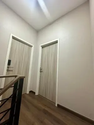 an empty room with two doors and wooden floors at The Gabriel House in Ban Bang Khen (1)