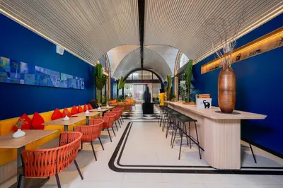 a restaurant with orange chairs and a blue wall at Hotel Bangkokian in Bangkok