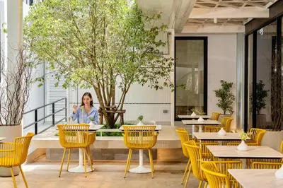 a woman sitting at a table in a restaurant at Hotel Bangkokian in Bangkok