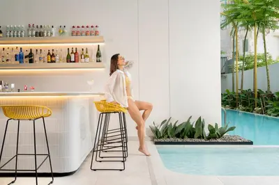 a woman sitting on a bar stool next to a pool at Hotel Bangkokian in Bangkok