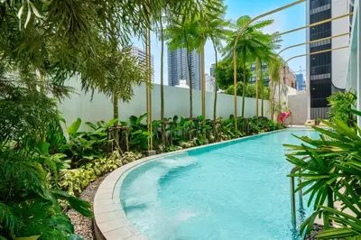 a swimming pool in a building with palm trees at Hotel Bangkokian in Bangkok