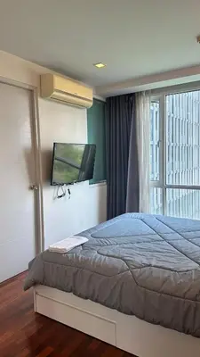 a bedroom with a bed and a tv on the wall at Spacious Sukhumvit Condo near EmQuartier in Bangkok