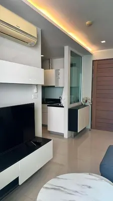 a modern kitchen with white cabinets and a blue chair at Spacious Sukhumvit Condo near EmQuartier in Bangkok