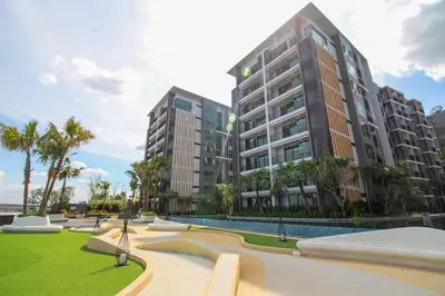 a large building with palm trees in a park at Metro luxe riverfront resort style condo in Ban Sai Ma