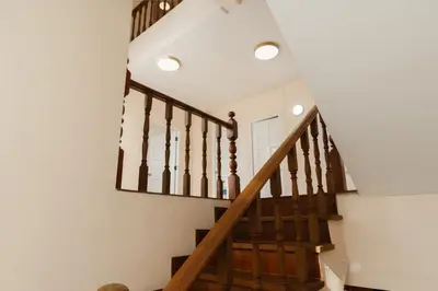 a staircase in a home with white walls and wooden railings at Charming 3-Storey house near BTS Onnut Station in Bangkok
