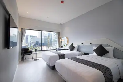 a hotel room with two beds and a large window at Queensland Hotel Bangkok in Bangkok