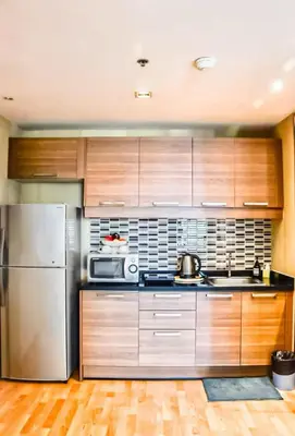 a kitchen with wooden cabinets and a stainless steel refrigerator at Spacious and Renovated 1-Bedroom 100m to Nana BTS - 55 sqm in Bangkok