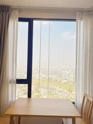 a wooden table in front of a large window at Cassia Rama9 Loft Highrise View Central in Bangkok