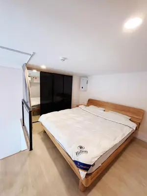 a bedroom with a large bed with white sheets at Cassia Rama9 Loft Highrise View Central in Bangkok