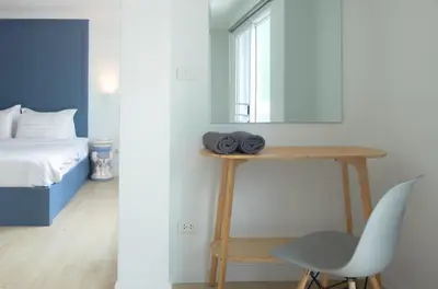 a bedroom with a bed and a table and a chair at Baan Khun Pra No 1 Bangkok Duplex in Bangkok