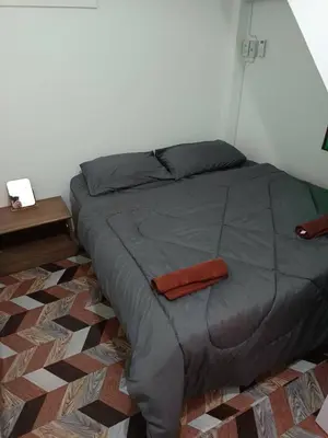 a bed with a gray comforter in a room at Sleep Break Hostel Sathon in Bangkok
