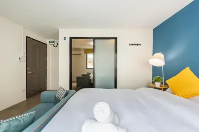 a bedroom with a large white bed and a blue wall at Lachata - Hua Mak in Bangkok
