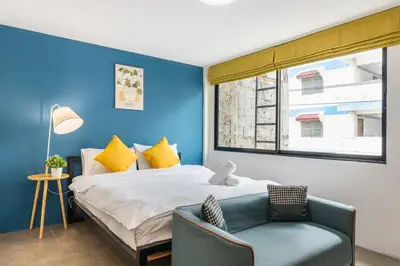 a bedroom with a large bed and a blue wall at Lachata - Hua Mak in Bangkok