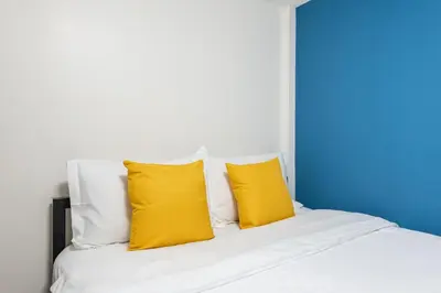 a white bed with two yellow pillows on it at Lachata - Hua Mak in Bangkok