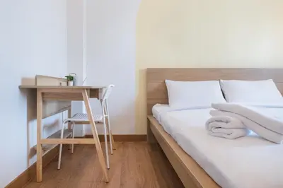 a bedroom with a bed and a table and a desk at Marshmallow House in Sathani Lak Si