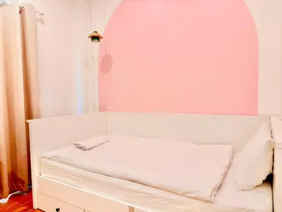 a bedroom with a white bed and a pink wall at Marshmallow House in Sathani Lak Si