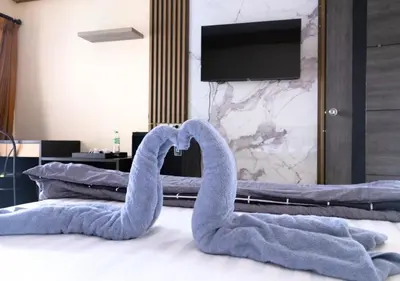 two towel swans laying on a bed with a tv at Cabanaz Pool Villa in Ban Zong Katiam