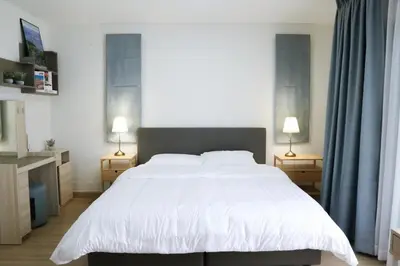 a bedroom with a large white bed and two lamps at Cozy Homey Place Townhome in Bangkok
