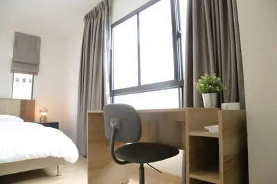 a bedroom with a chair and a bed and a window at Cozy Homey Place Townhome in Bangkok