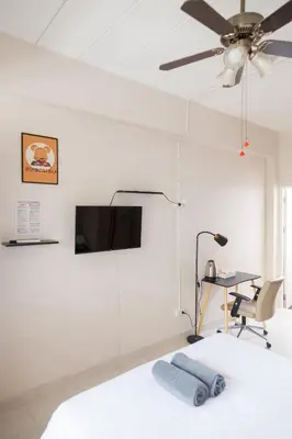 a bedroom with a ceiling fan and a desk at Relax Inn DMK in Lak Si