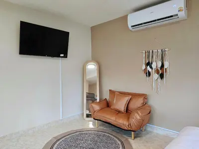 a living room with a leather chair and a tv at Relax Inn DMK in Lak Si