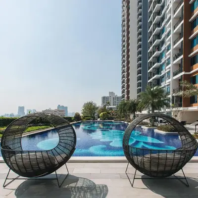 two wicker chairs sitting next to a swimming pool at Beautiful Studio Room Near MRT in Bangkok