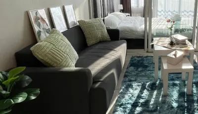 a living room with a couch and a bed at Beautiful Studio Room Near MRT in Bangkok