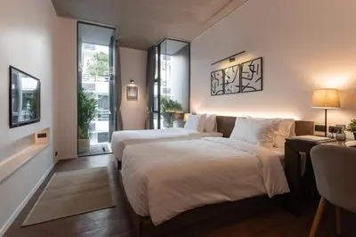 a bedroom with two beds and a window at Norma Hotel Sathorn in Bangkok