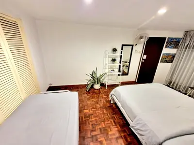 a bedroom with two beds and a potted plant at Home16 Sukhumvit16 in Bangkok