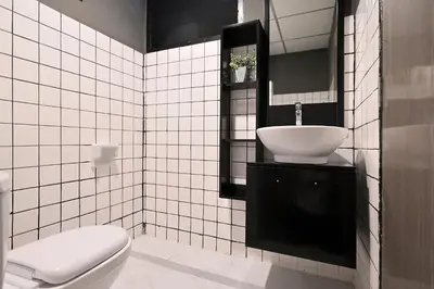 a white tiled bathroom with a toilet and a sink at Floton Bangkok Hotel in Bangkok