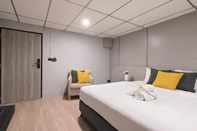 a bedroom with a large white bed with yellow pillows at Floton Bangkok Hotel in Bangkok