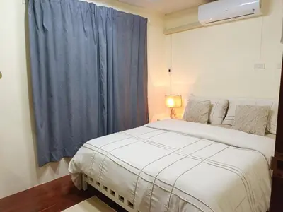 a bedroom with a white bed and a blue curtain at Retreat House 81 - BTS Onnut in Bangkok