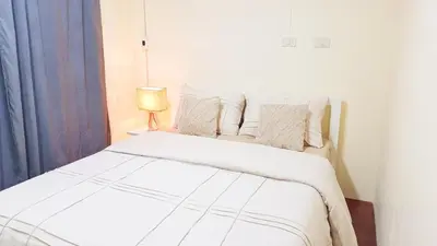 a bedroom with a large white bed with a lamp at Retreat House 81 - BTS Onnut in Bangkok