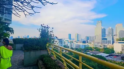 a person sitting on a ledge looking at a city at River View 8 in Yan Nawa