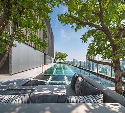 a swimming pool on the side of a building with trees at Phrom Phong Top 1BD pool,gym,park and mall BTS in Khlong Toei