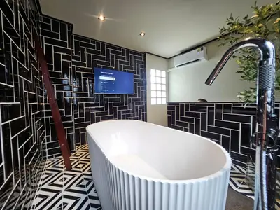 a bathroom with a tub and a tv on a wall at Soho Heritage House China Town Bangkok in Bangkok
