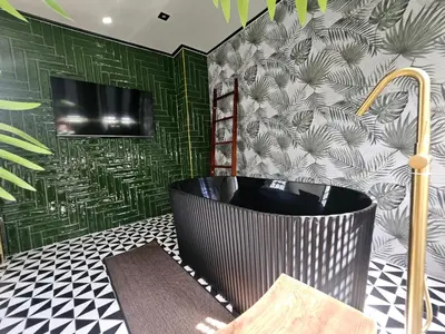 a bathroom with a black tub and a green wall at Soho Heritage House China Town Bangkok in Bangkok