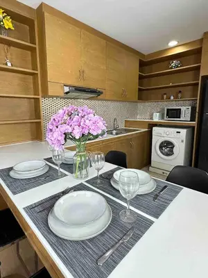 a kitchen with a table with plates and flowers on it at convenient&peaceful place in Soi nai leot in Bangkok
