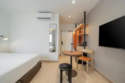 a bedroom with a bed and a desk and a tv at Asoka Hotel at Asoke Makkasan in Bangkok