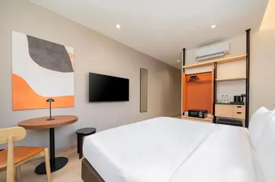 a bedroom with a bed and a desk and a tv at Asoka Hotel at Asoke Makkasan in Bangkok