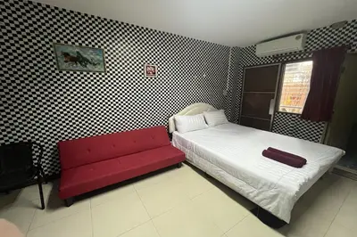 a bedroom with a bed and a red couch at Green Place 107 in Bangkok