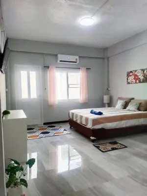 a bedroom with a large bed and two windows at The Little home in Ban Khlong Mae Nam Bon