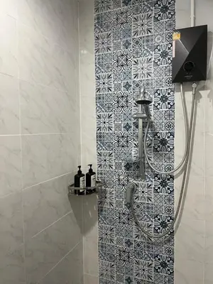 a bathroom with a shower with a tile wall at Baan Saen Saran residence in Sathani Bang Ramat