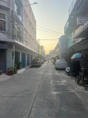an empty street with cars parked on the sides of buildings at JC home \u5218 \u5148 \u751f in Bangkok