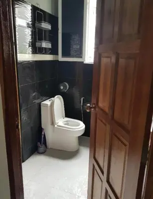 a bathroom with a toilet with black walls and a door at Jatujak Bangkok guesthouse R3 in Sathani Bang Su