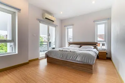 a bedroom with a large bed and two windows at Modern Townhouse City Center 4 Floors 13 Guests in Bangkok