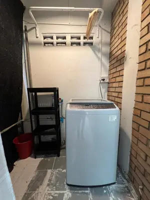 a washing machine in a garage with a brick wall at 3 bedrooms 2 bathroom's in Bang Su