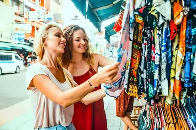 two women looking at clothes in a store at XX GO INN Khaosan - ตรอกข้าวสาร กรุงเทพ in Bangkok