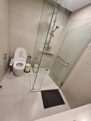 a bathroom with a toilet and a glass shower at Comfortable Zone in Khlong Toei