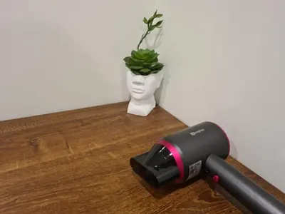 a hair dryer on a table with a plant in a vase at Comfortable Zone in Khlong Toei